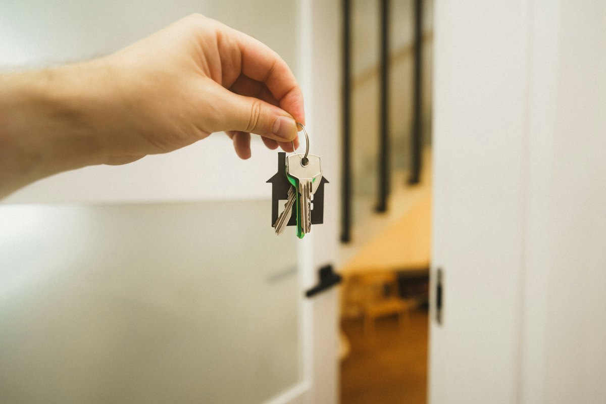 Hand hält einen Schlüssel an der Wohnungstür